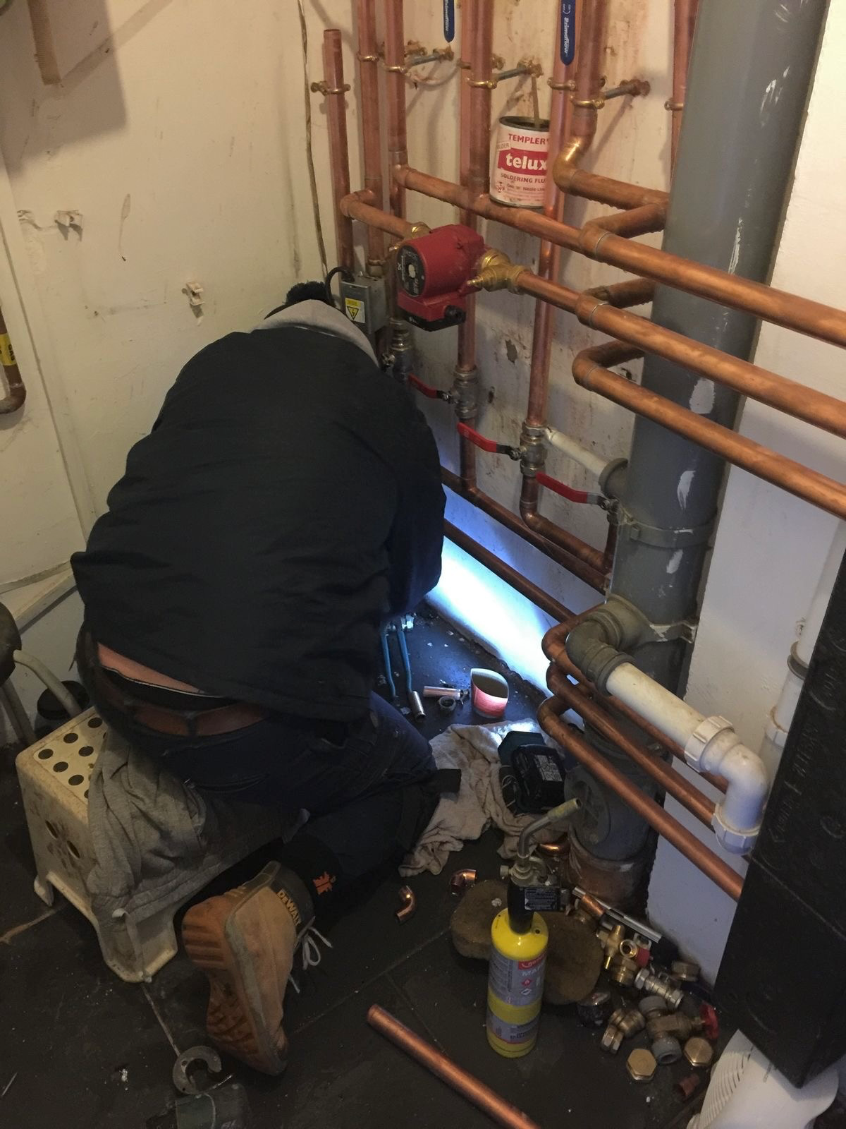 Professional plumber working on copper pipework and central heating system in a London property